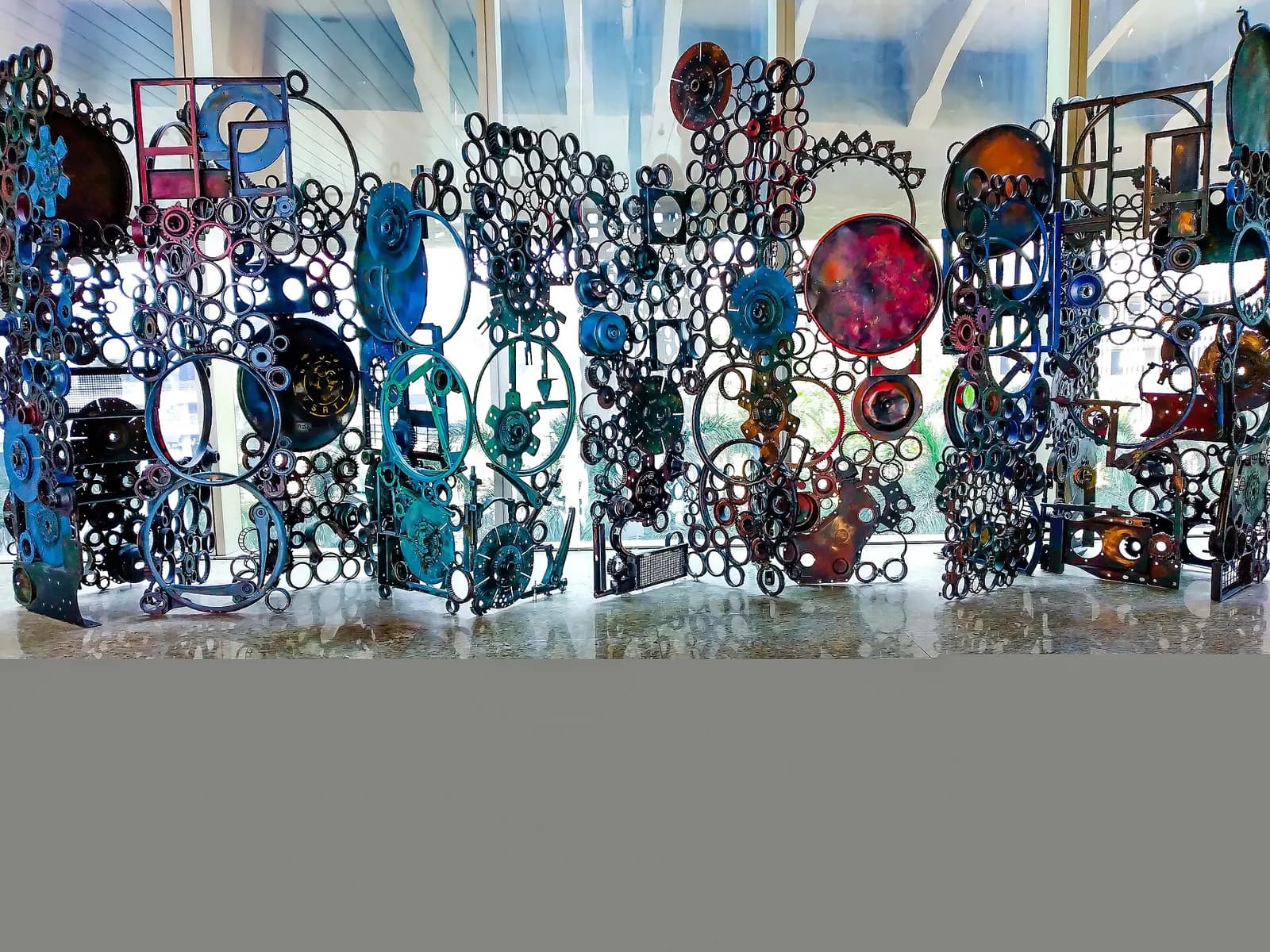 A large sculptural artwork made from welded metal parts stands on display inside the airport terminal.