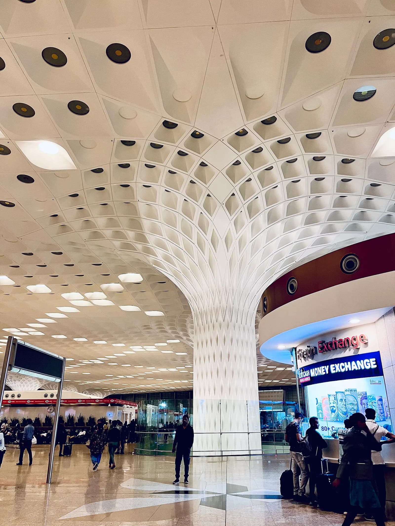 A bright, vaulted departure hall with white structural columns, high ceilings, and large windows filling the Skidmore, Owings & Merrill-designed interior with natural light.