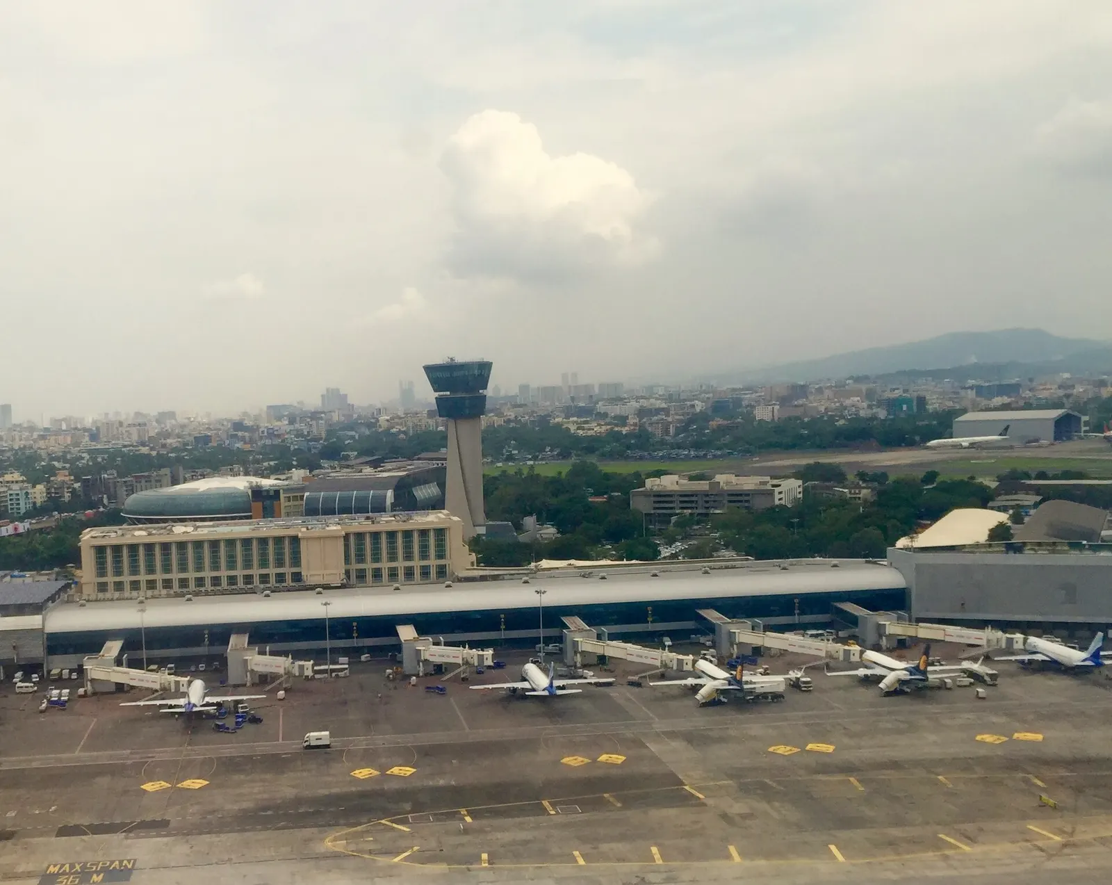 An aerial view shows Terminal 1C's flat-roofed buildings and apron, with the airport hotel and control tower visible behind the domestic terminal complex.