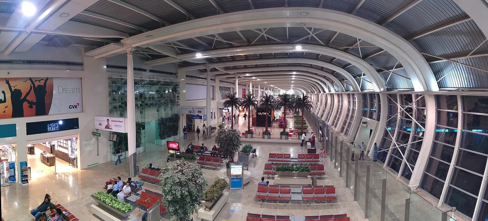 A wide panoramic view captures multiple low-rise terminal buildings, jet bridges, and parked aircraft across Mumbai's domestic airport campus.