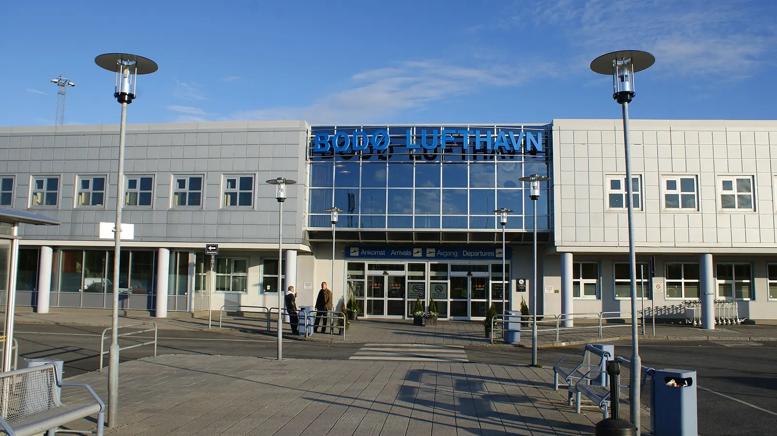Modern glass terminal exterior at Bodø Airport with the control tower behind.