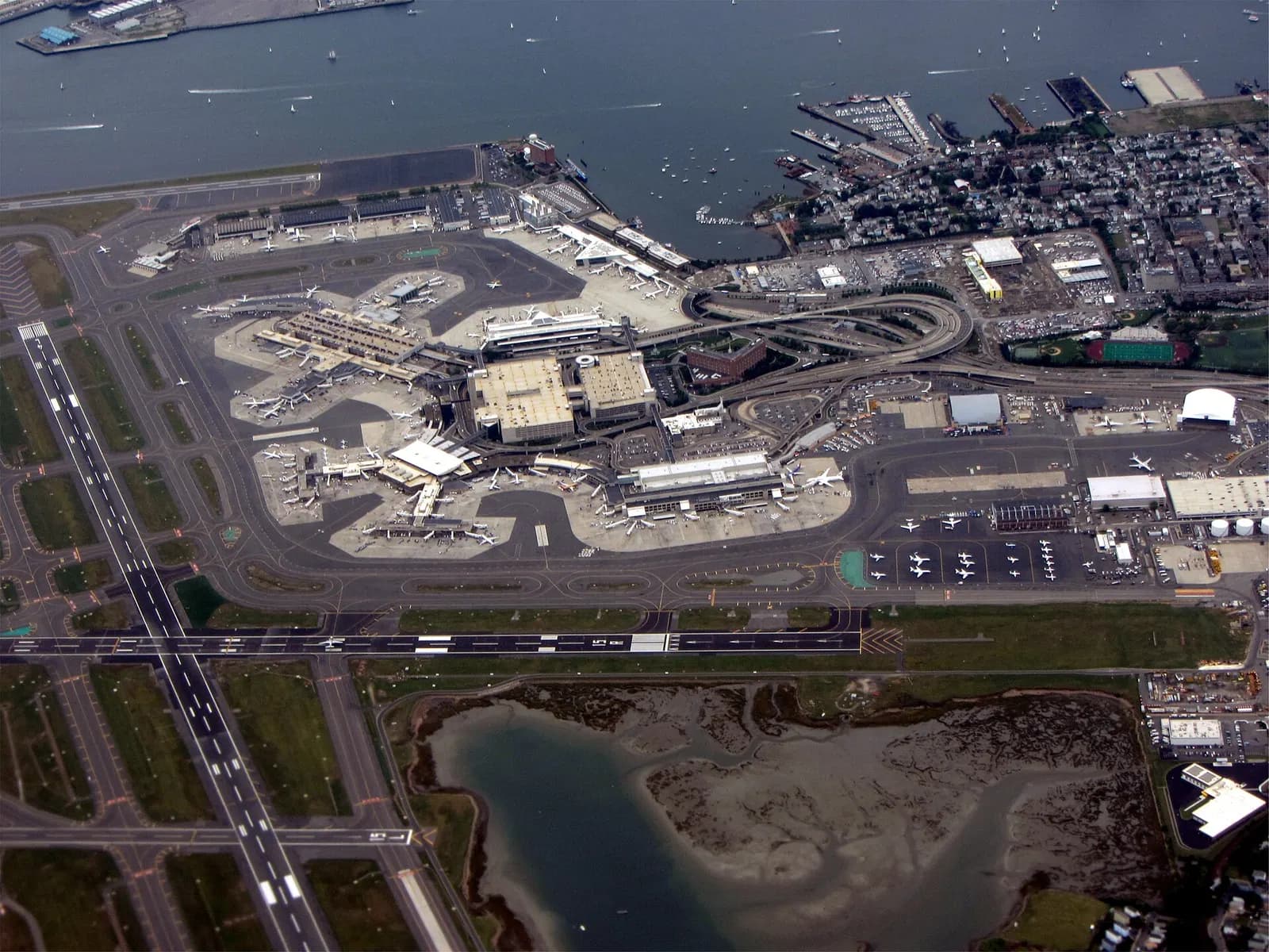 An aerial view shows Logan's runways, terminals, and surrounding water on the East Boston peninsula.