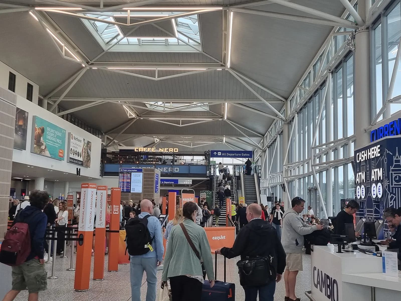 Wide view of the Bristol Airport check-in hall with desk banks and passengers in July 2024