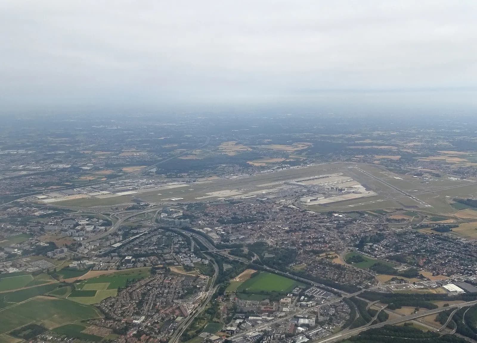 The main terminal buildings and aircraft parking areas at Brussels Airport in Zaventem, seen from outside on a clear day.