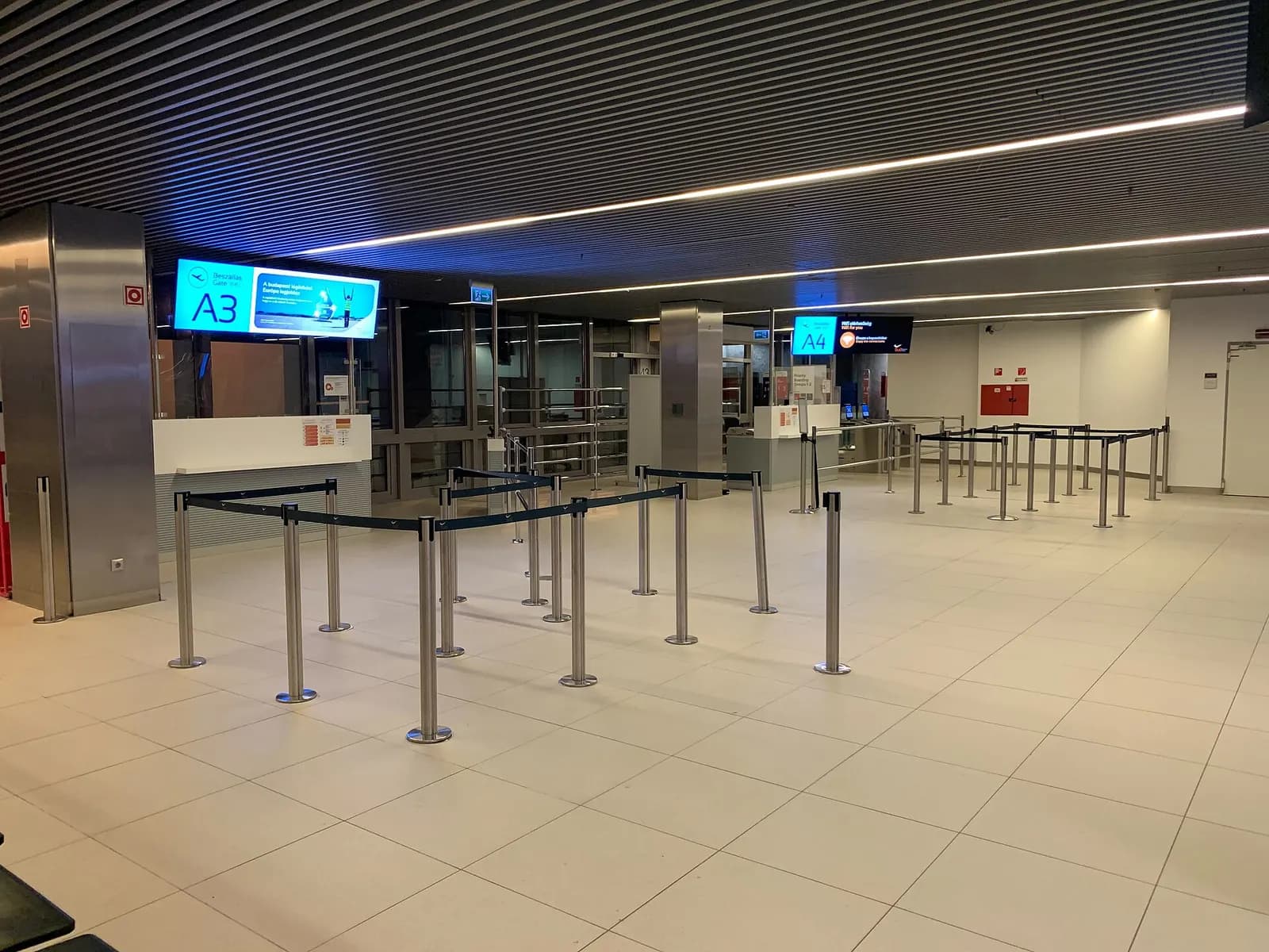 A gate seating area at gates A3 and A4 in Terminal 2, with rows of chairs and large windows facing the apron.