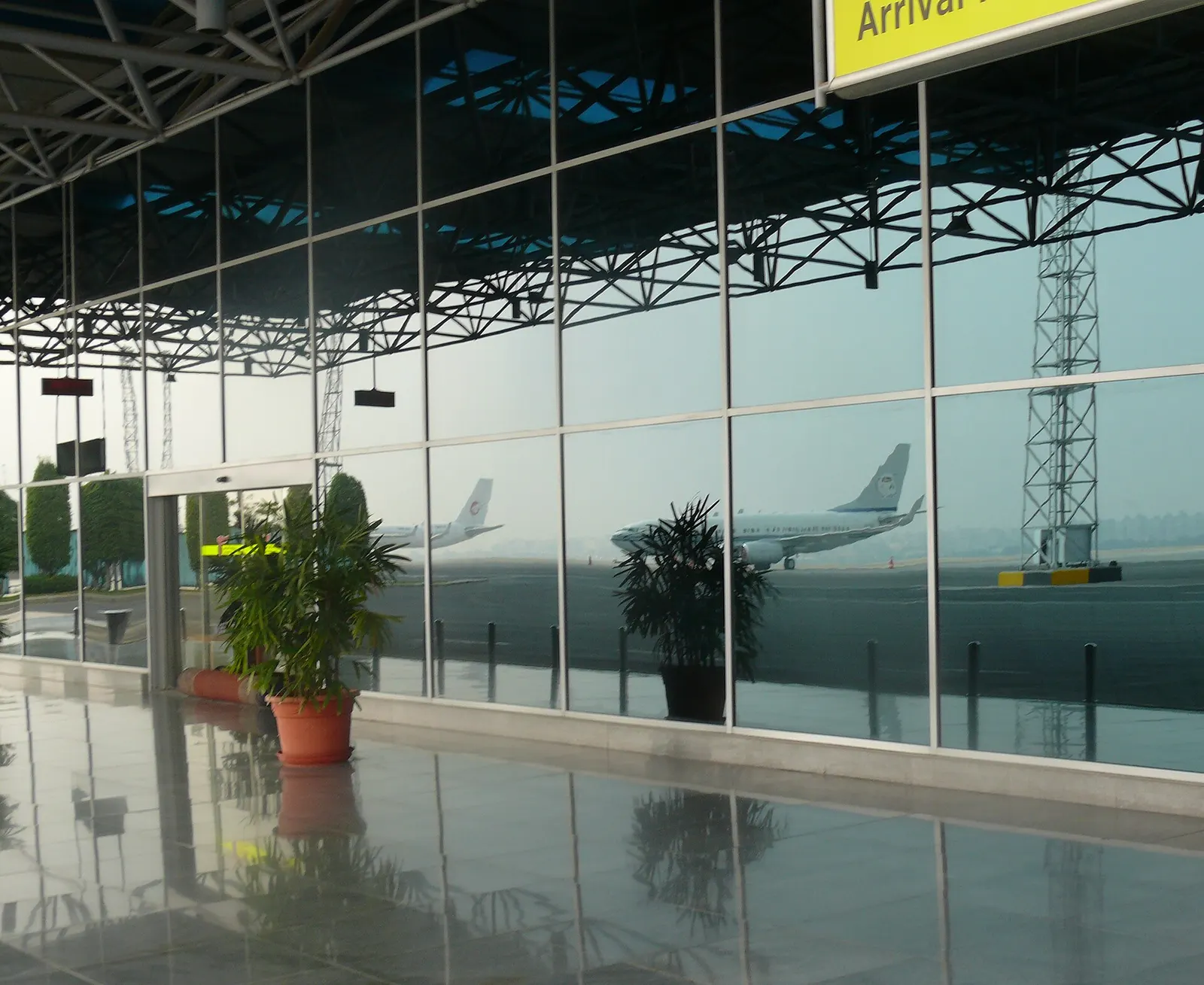 The arrivals hall at Cairo International Airport seen through large windows reflecting terminal architecture and outdoor light.