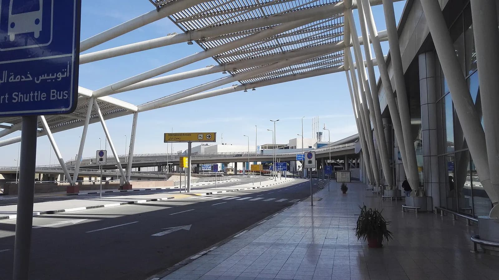 Terminal 3 at Cairo International Airport with a shuttle bus stop and covered waiting area in the foreground.