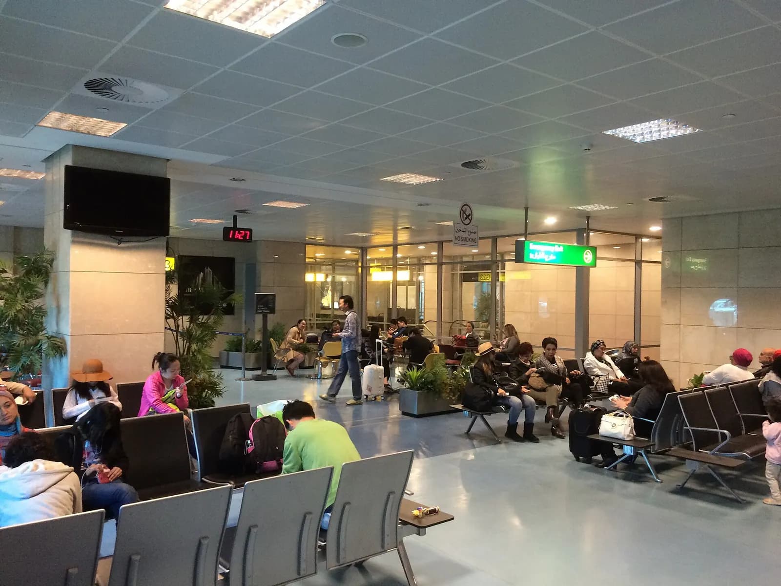 A departure gate seating area in Terminal 3 at Cairo International Airport with rows of chairs facing large windows.