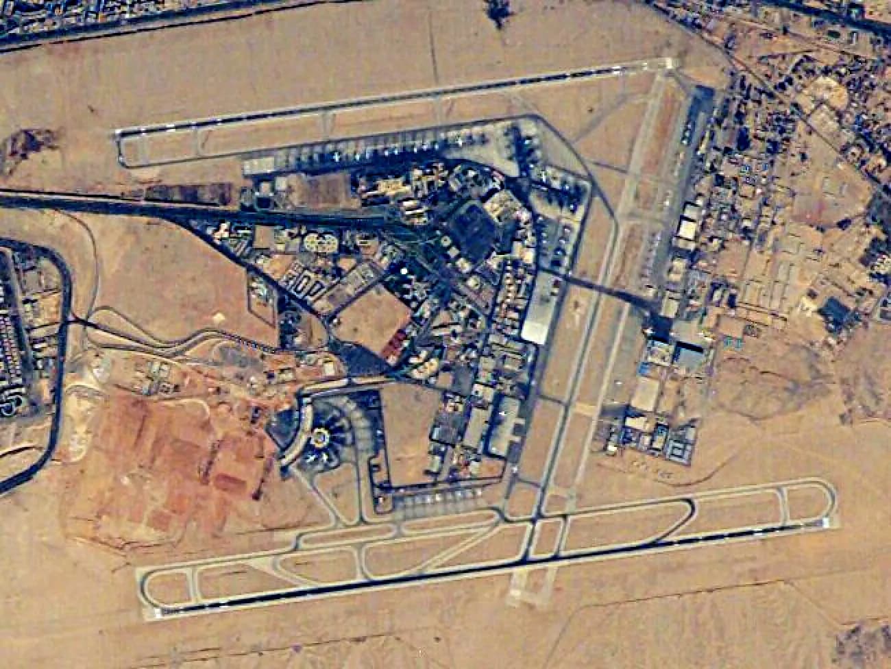 Aerial satellite view of Cairo International Airport showing runways, terminals, and surrounding urban development.