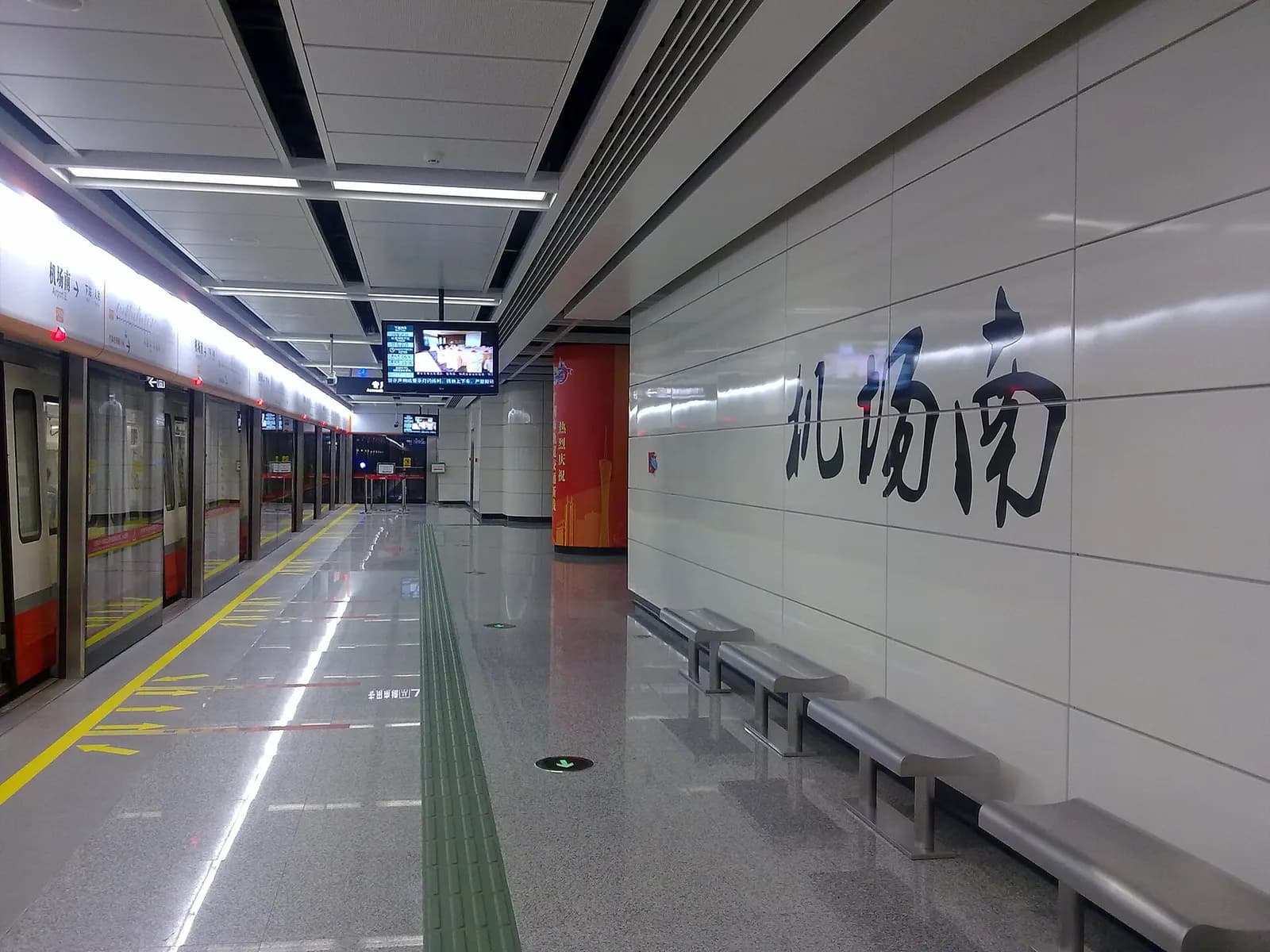 The platform at Metro Airport South Station with platform screen doors, a stopped train, and fluorescent lighting in the tunnel.