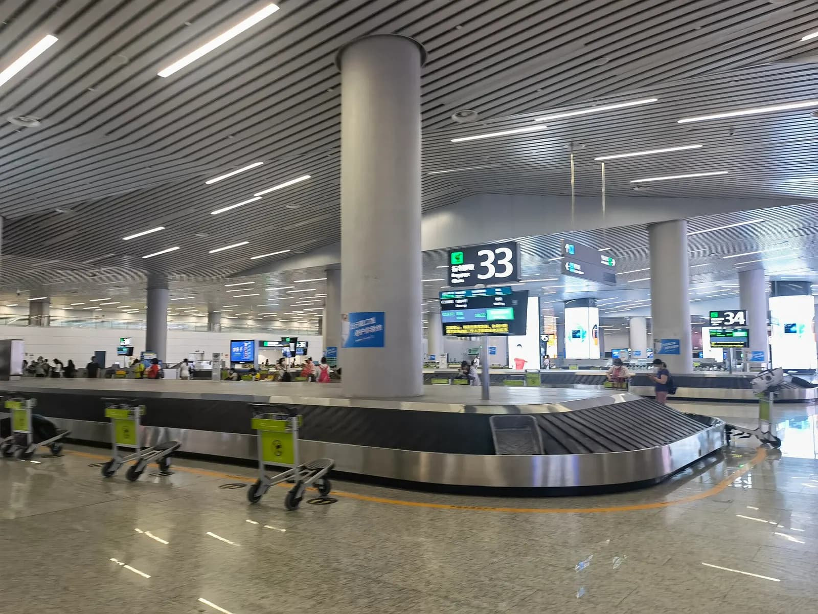 The domestic baggage-claim hall in Terminal 2 with multiple luggage carousels, overhead signs, and arriving passengers.