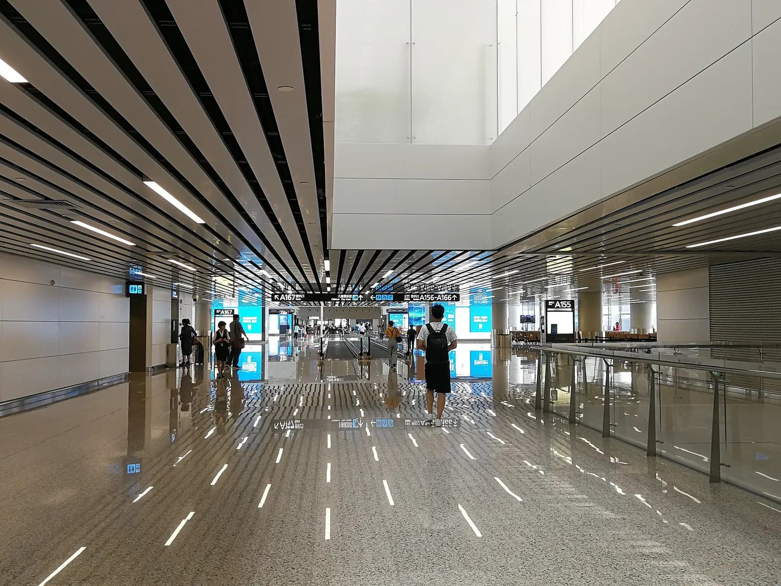 A wide international-departures concourse in Terminal 2 with gate seating areas, retail shops, and flight-information screens.