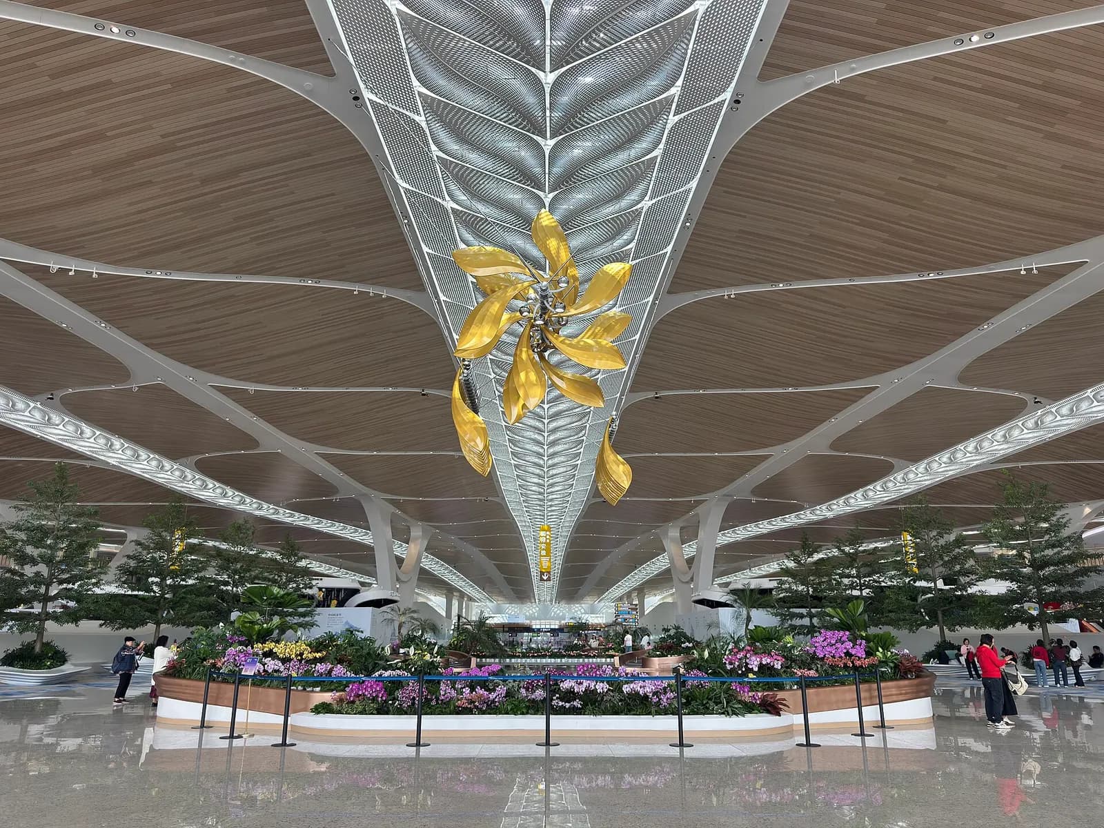 A bright, high-ceilinged main concourse inside Guangzhou Baiyun Airport Terminal 3 filled with travelers, shops, and overhead flight-information displays.