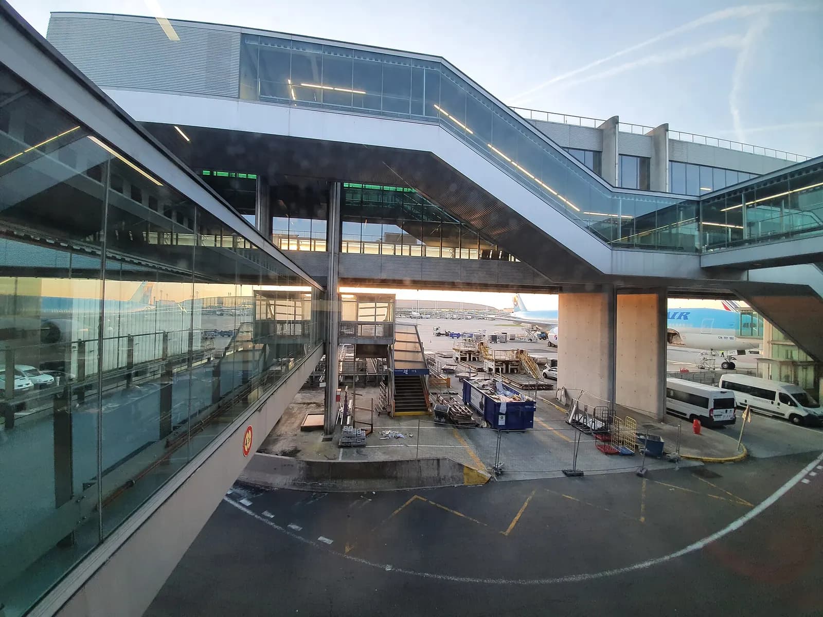 Terminal 2's curved satellite buildings and glass facades glow in the evening light at dusk.