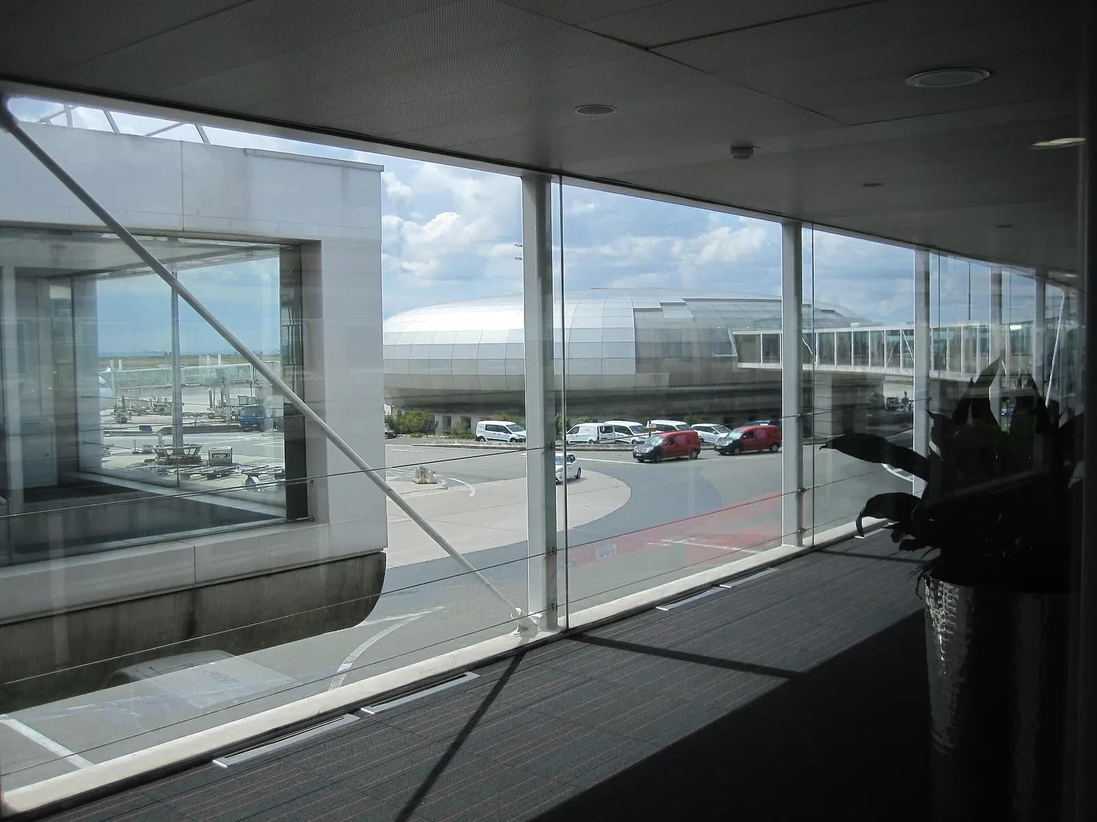 The modern glass-and-steel exterior of the Terminal 2A annex on a clear summer day.