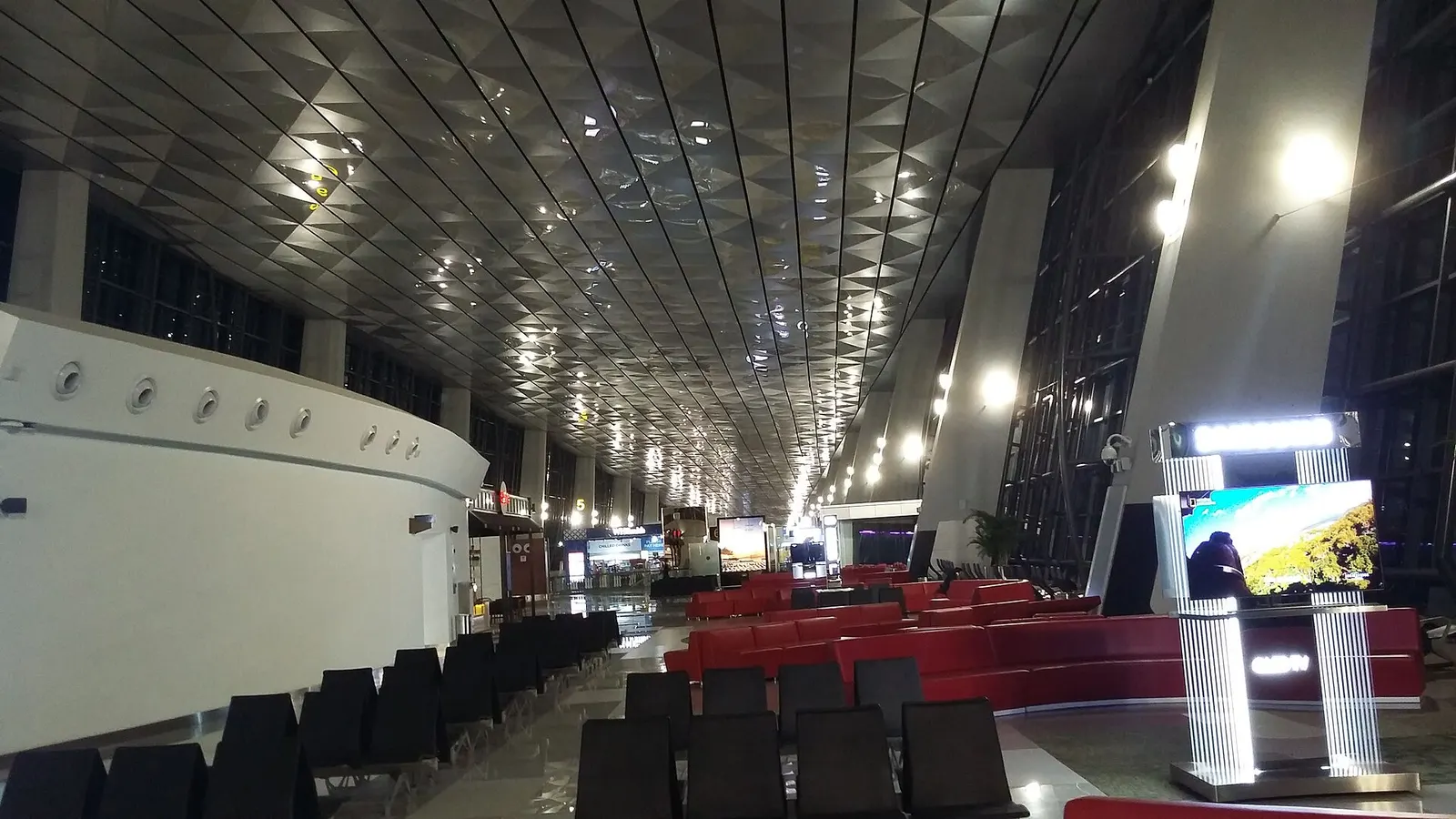 Spacious international departure waiting area in Terminal 3 with high ceilings, rows of seating, and gate signage visible along the concourse.