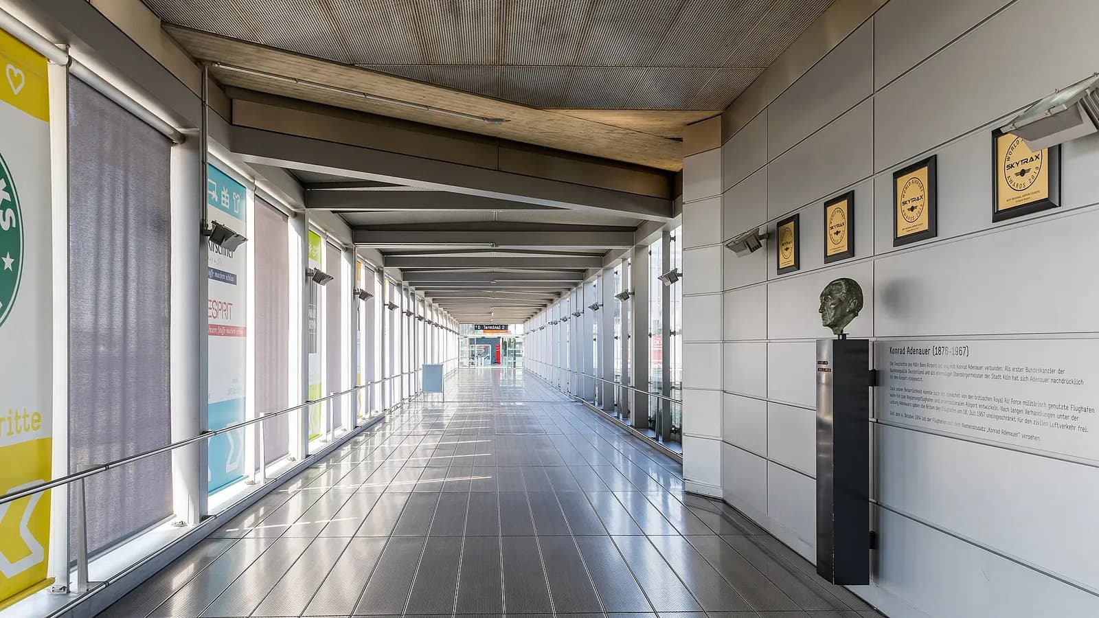 The enclosed pedestrian walkway connecting Terminal 1 and Terminal 2 at Cologne Bonn Airport.