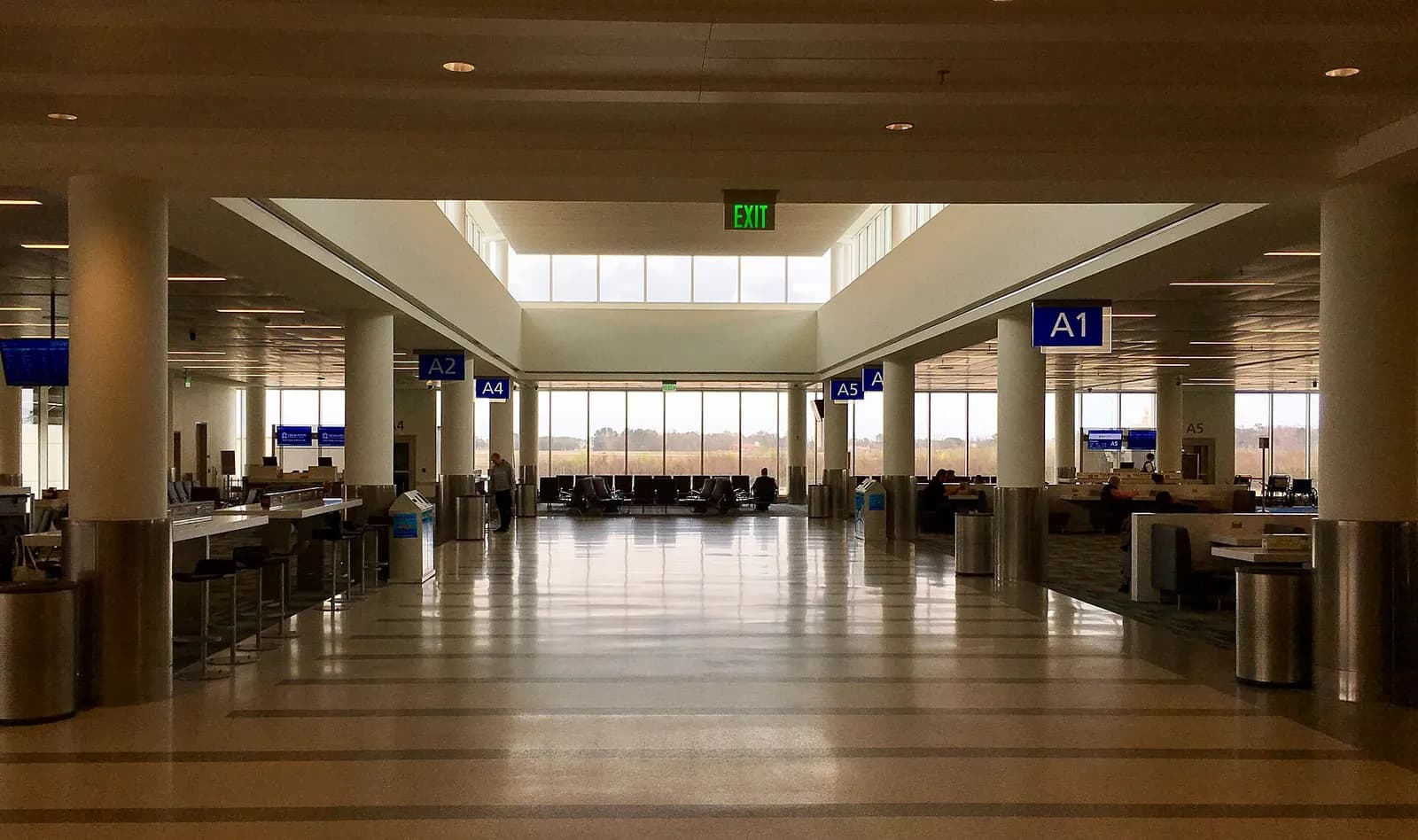 Open Concourse A holdroom at Charleston International with hanging gate signs A1, A2, A4 and A5 and floor-to-ceiling windows.