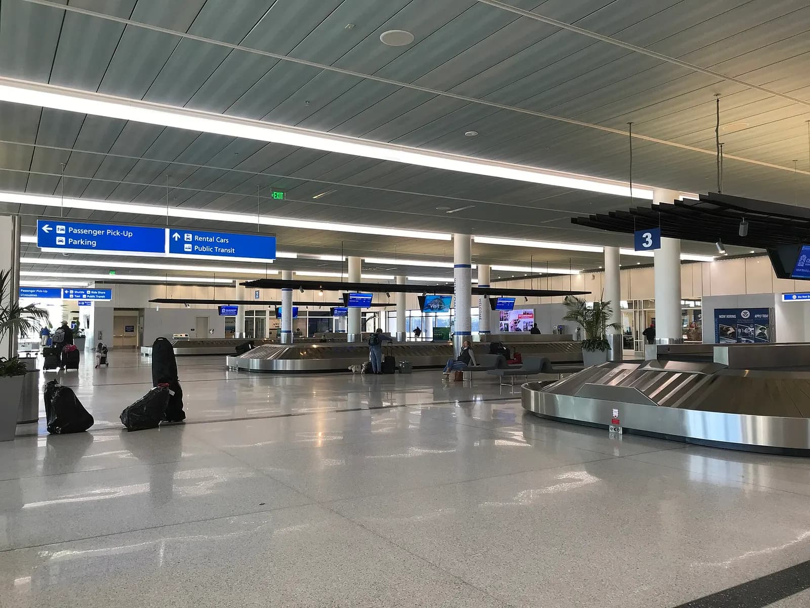 Charleston International baggage claim with carousel 3, a mostly empty hall, and overhead signs for passenger pickup, rental cars, parking and the public exit.