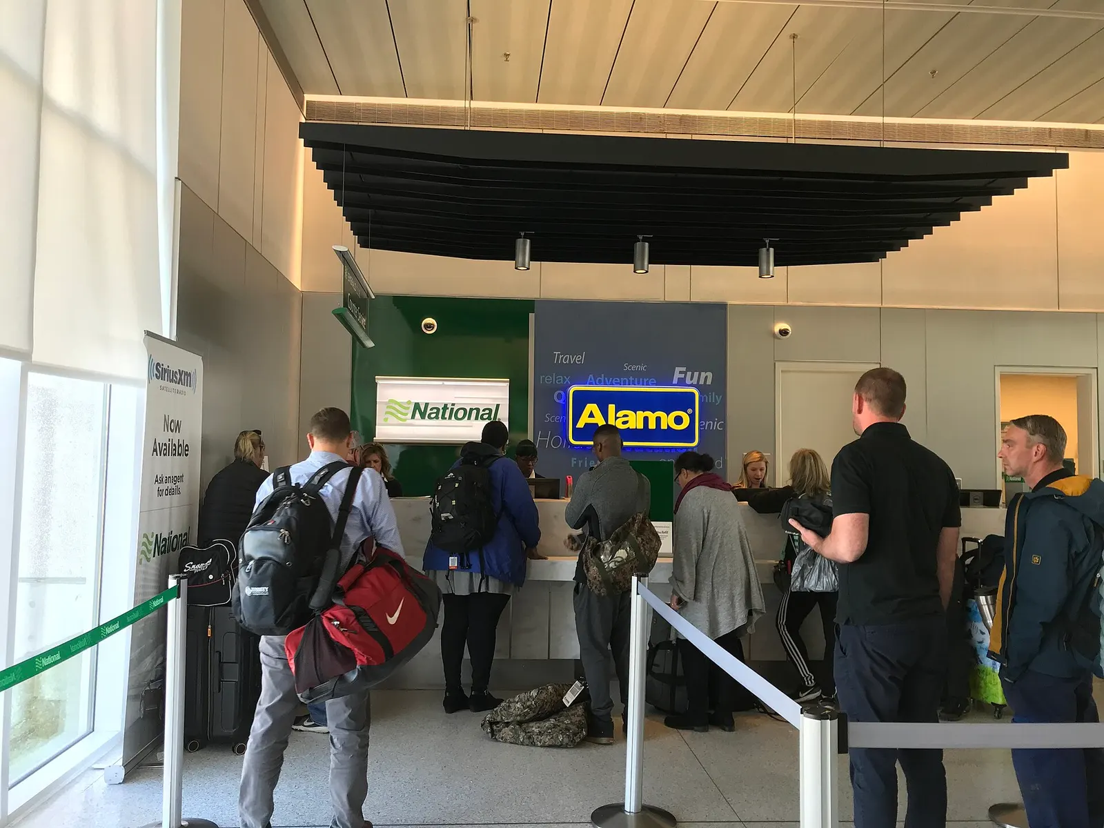 In-terminal rental counters at Charleston International labeled National and Alamo, with travelers waiting in a stanchioned line.