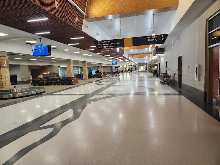 Landside baggage claim and rental-car counters at The Eastern Iowa Airport in January 2023, with the Mississippi River floor mural.
