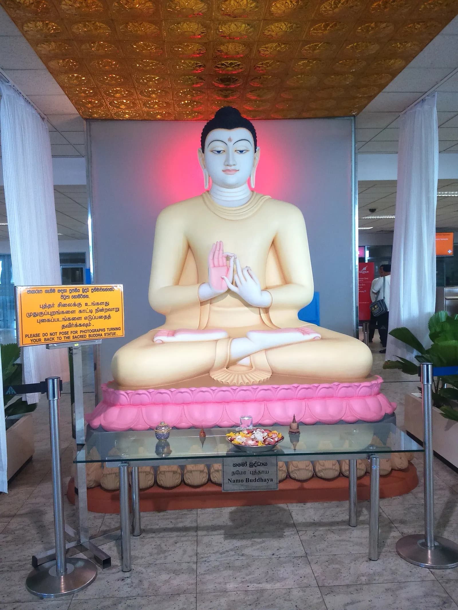 Buddha statue and trilingual courtesy sign inside Bandaranaike International Airport