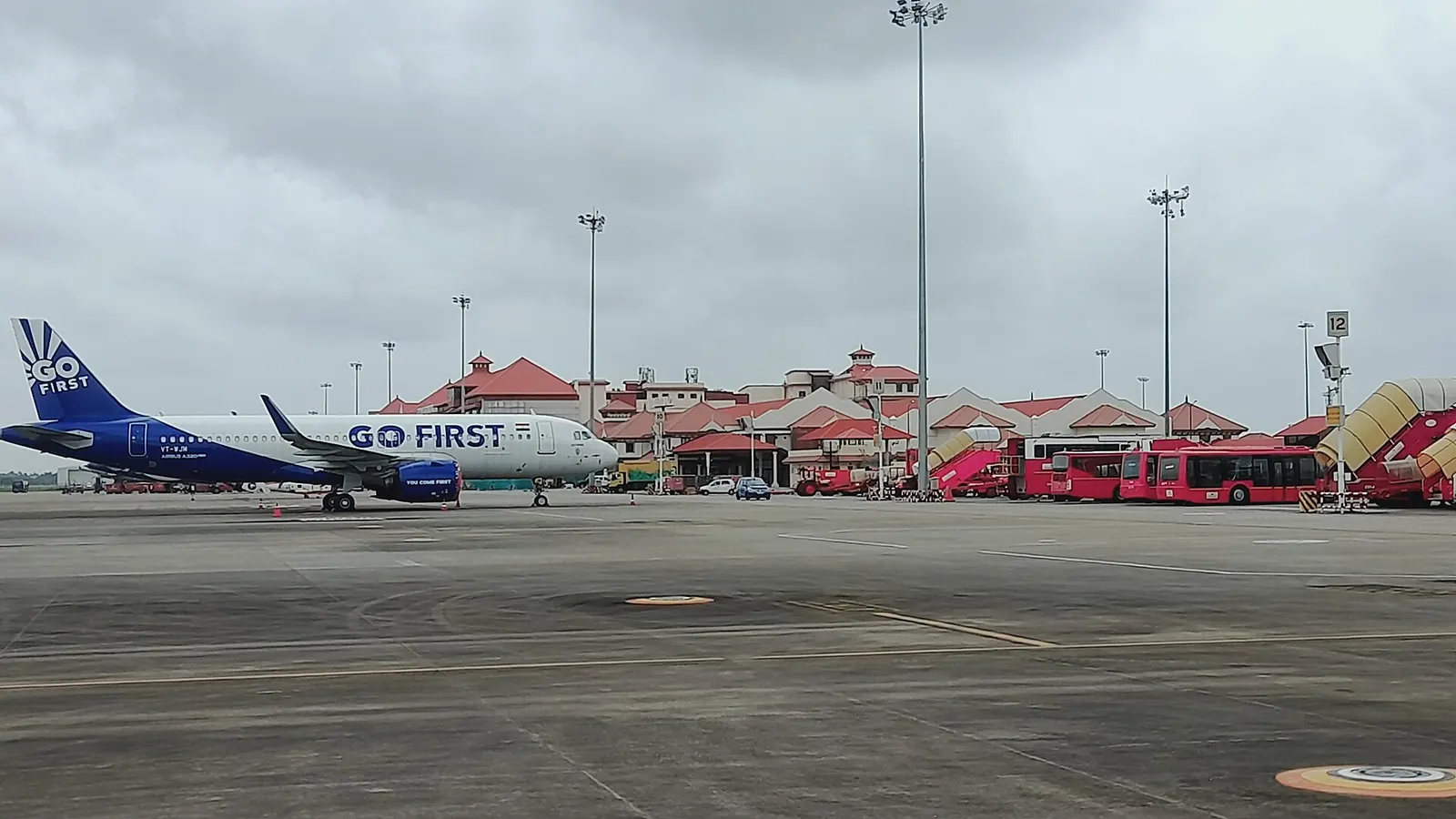 Go First A320neo VT-WJM on the Cochin apron with red-tiled terminal roofs behind