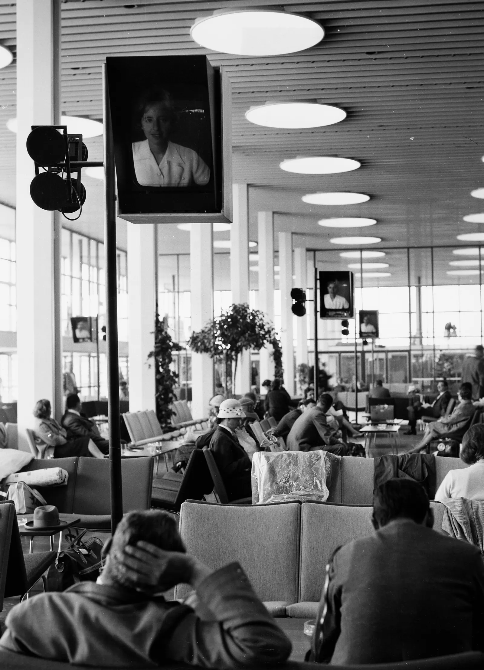 The spacious departure hall with flight-information displays, seating, and passengers beneath a high ceiling.