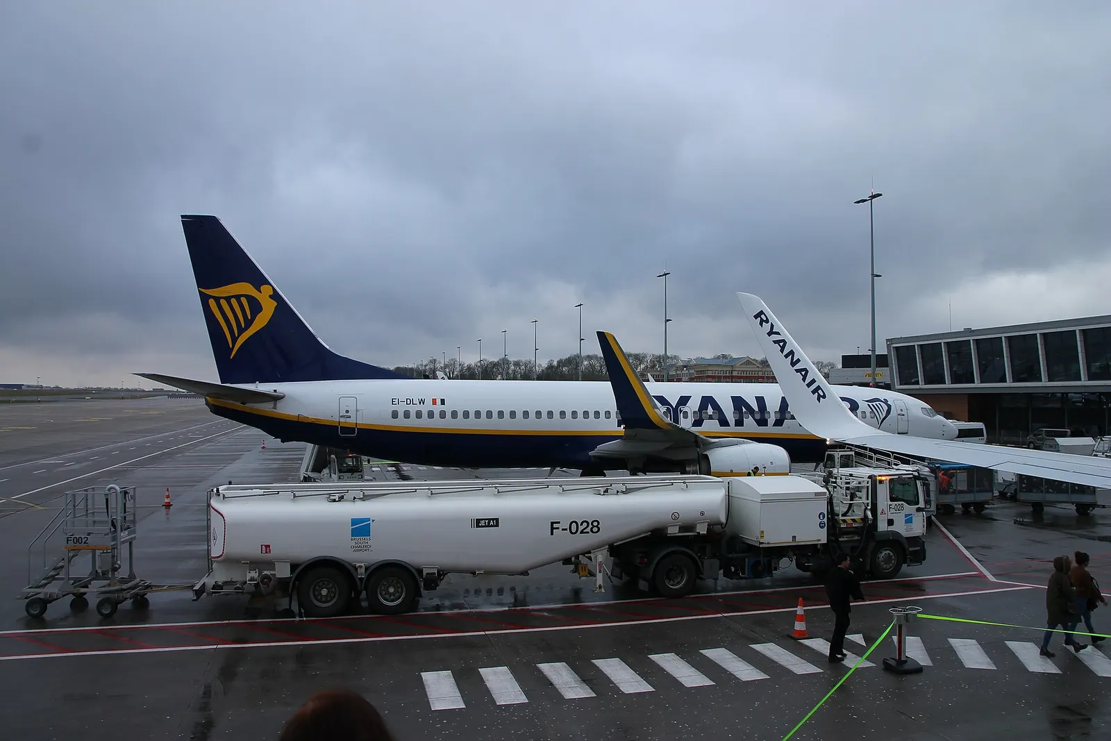 Jet A1 fuel truck marked Brussels South Charleroi Airport beside a Ryanair 737 on a rainy apron.