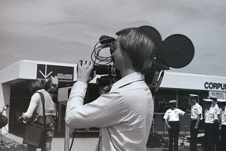 1976 black-and-white curb of the pre-Hayden Head Corpus Christi terminal, with a DEPLANING PASSENGERS sign and a news camera crew