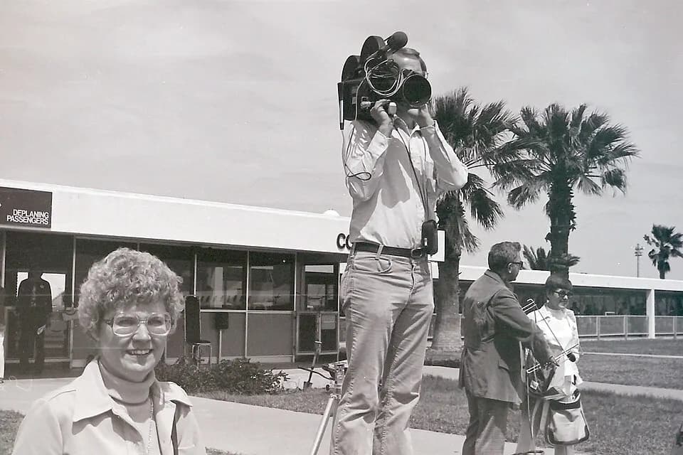 1976 high-angle view of the old Corpus Christi passenger hall with palms and a news cameraman