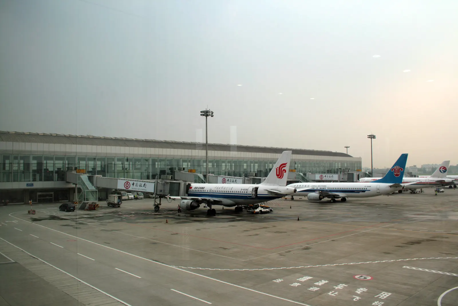 Airside Concourse C with gate holdrooms, moving walkways, and large windows overlooking the apron.
