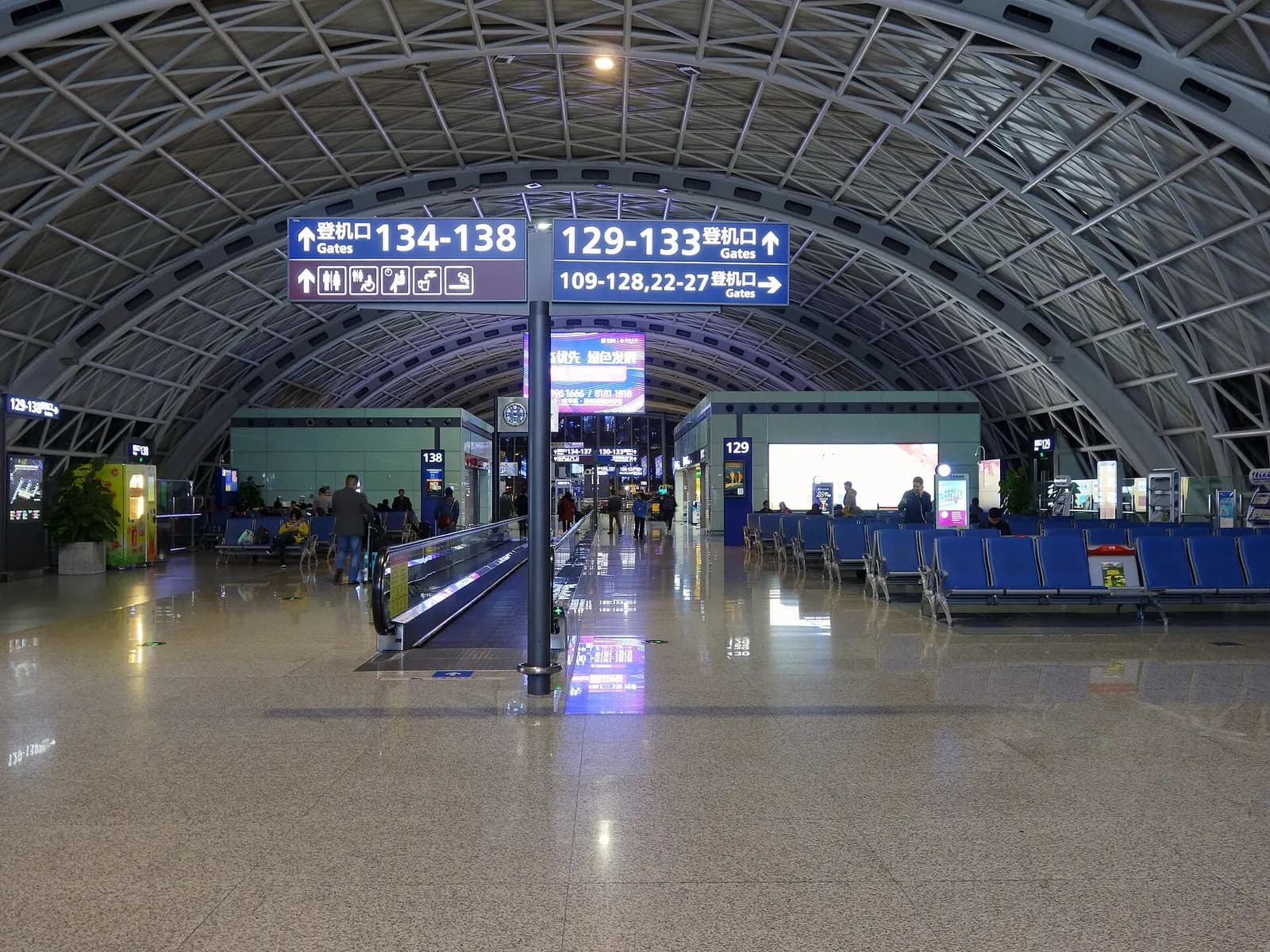 Spacious Terminal 2 waiting hall with departure gates, seating areas, and passengers beneath a high ceiling.