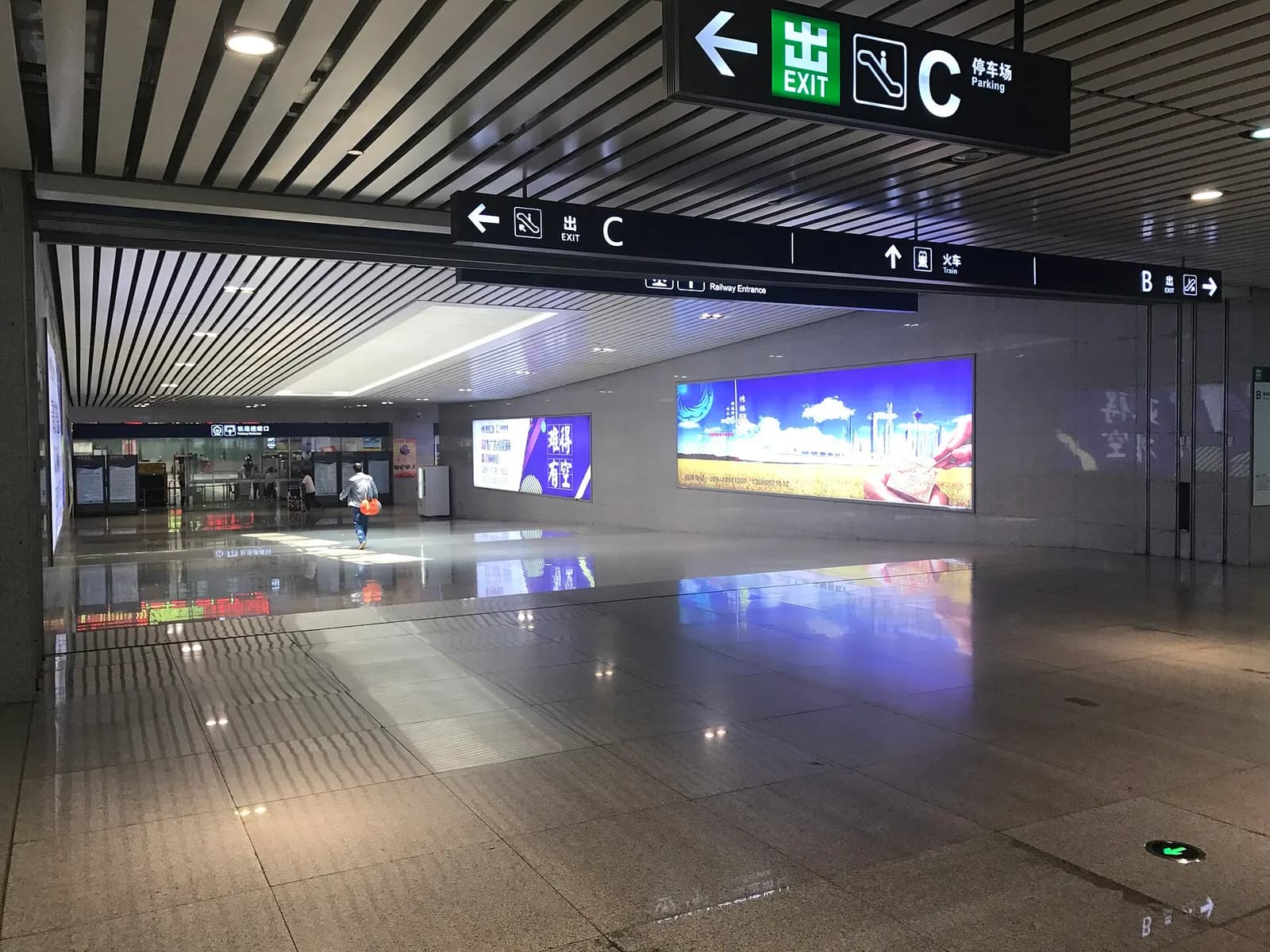 Indoor walkway in the airport metro station with signs pointing toward Shuangliu Airport Railway Station.