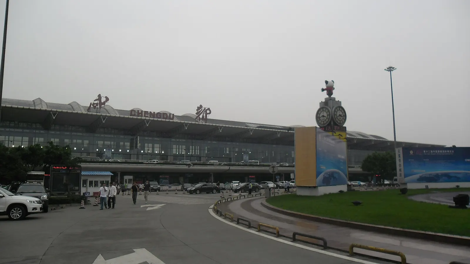 Wide exterior view of Chengdu Shuangliu International Airport Terminal 1 with its curved roofline, glass facade, and forecourt in front.