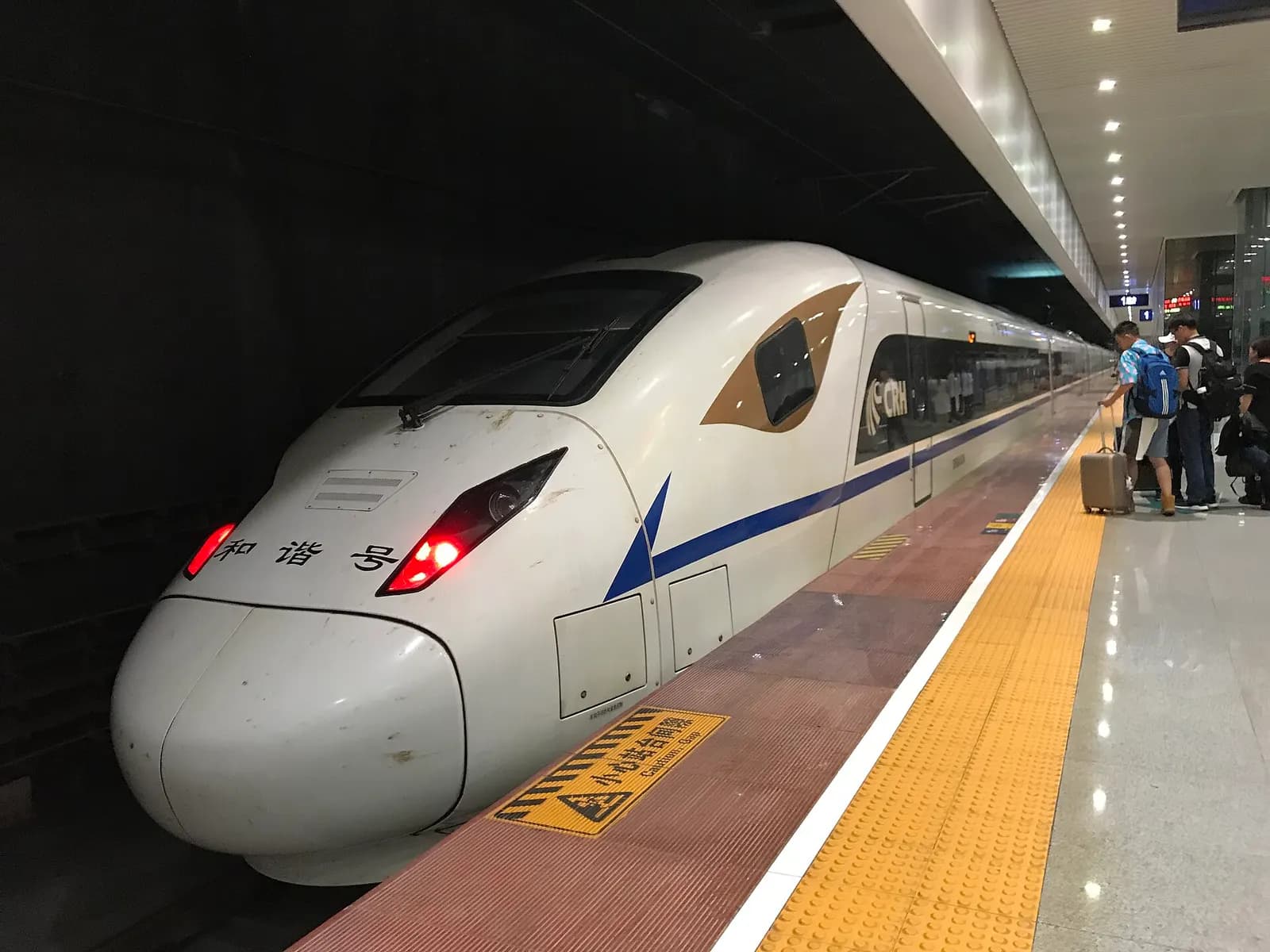 A CRH high-speed train stopped at Shuangliu Airport Railway Station platform beside platform markings and overhead signage.