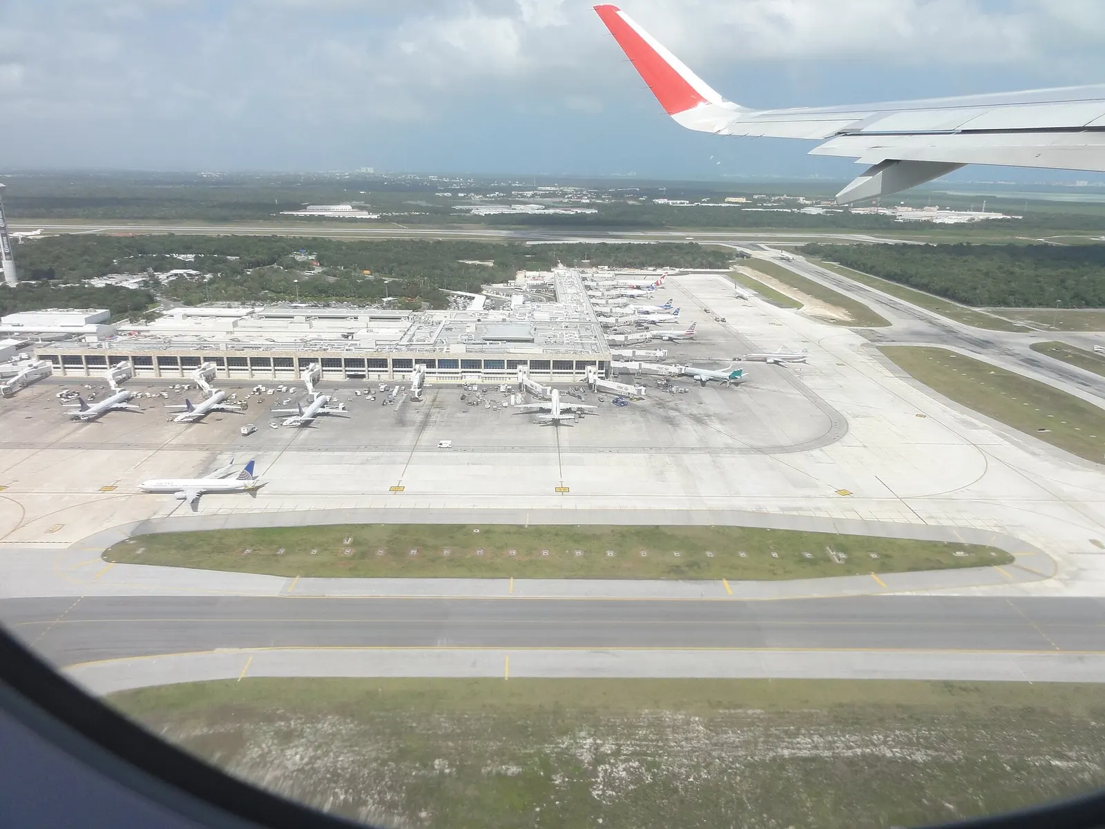 Ground-level view of Cancún International Airport showing terminal buildings and the surrounding airfield.