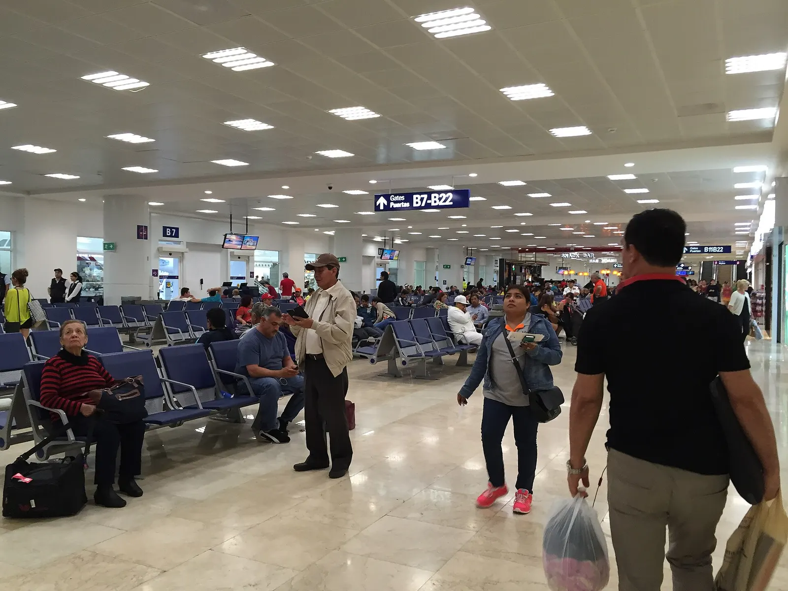 Passengers seated and walking through the gate concourse in Sala B of Terminal 2.