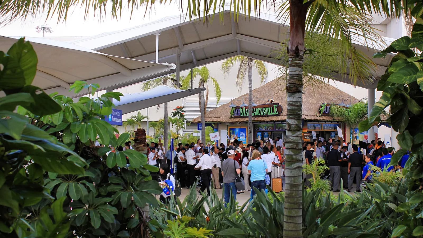 Air Margaritaville bar stand in the arrivals hall at Cancún International Airport with tropical branding.