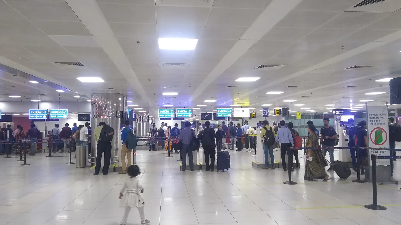 Long row of airline check-in counters and overhead flight information displays in the Terminal 2 departures hall at Delhi's Indira Gandhi International Airport.