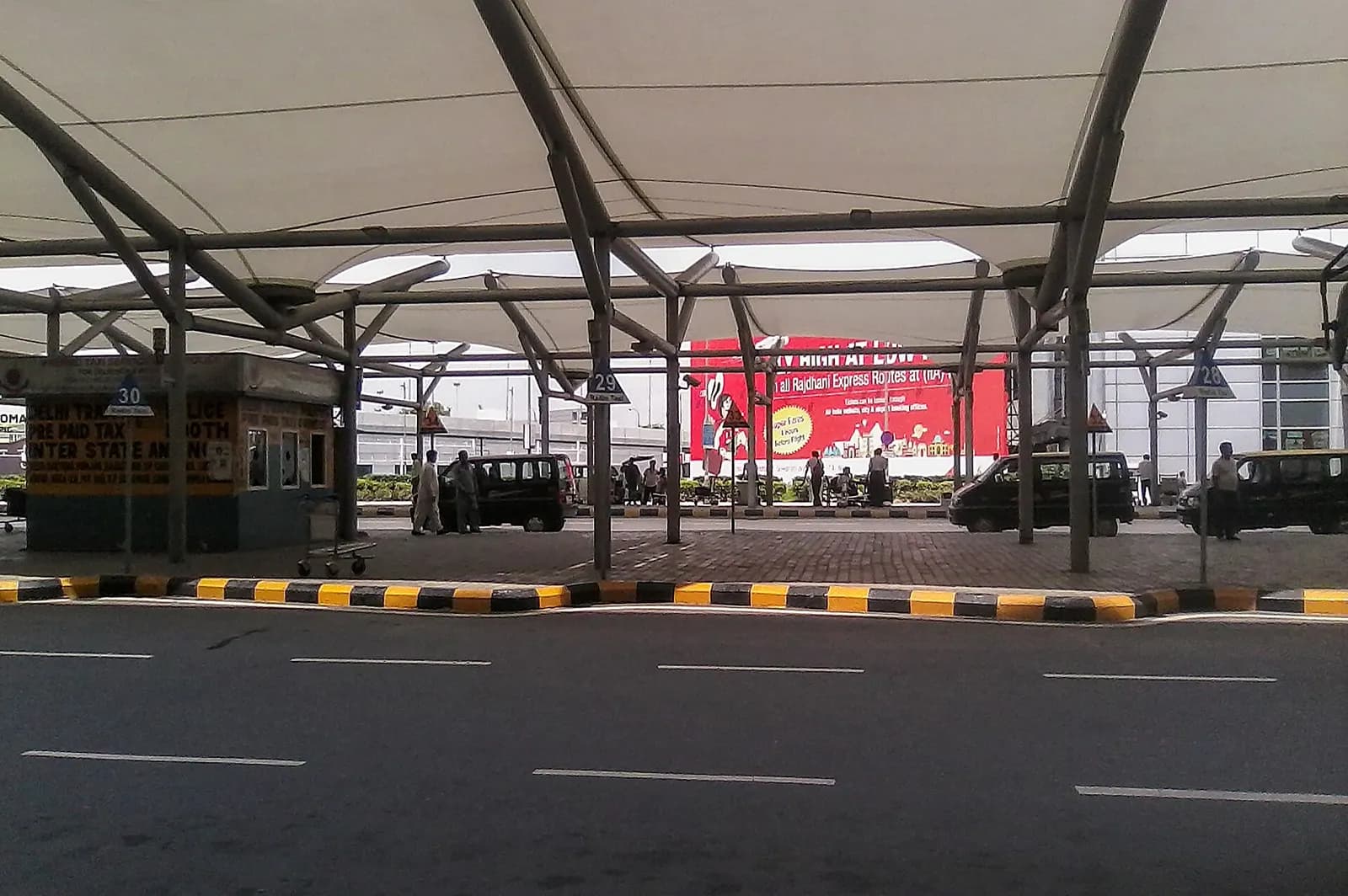 Terminal 2B approach road at Indira Gandhi International Airport with landscaped medians, signage, and terminal buildings ahead.