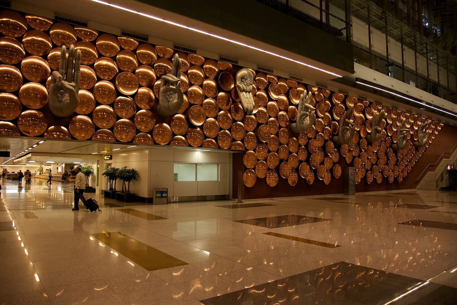 Large sculpted hands artwork displayed in the public area of Terminal 3 at Indira Gandhi International Airport.