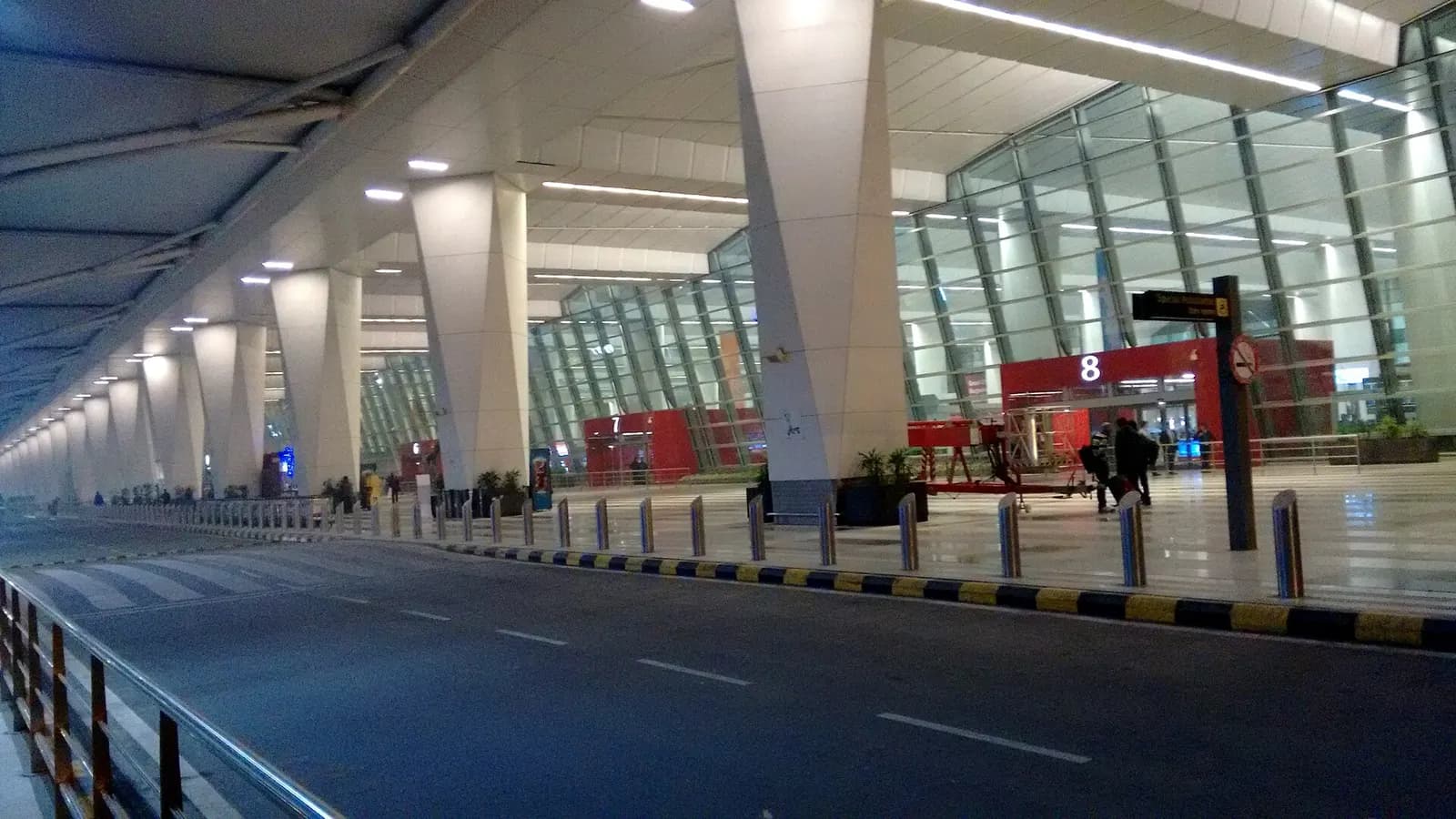 Curbside exterior of Terminal 3 at Indira Gandhi International Airport showing the large modern façade and approach roadway.