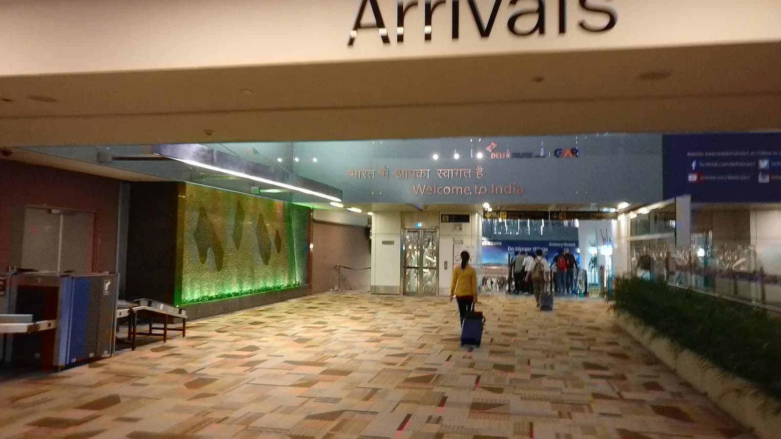 Wide view of the international arrivals hall at Terminal 3 with baggage reclaim belts, signage, and passengers collecting luggage.