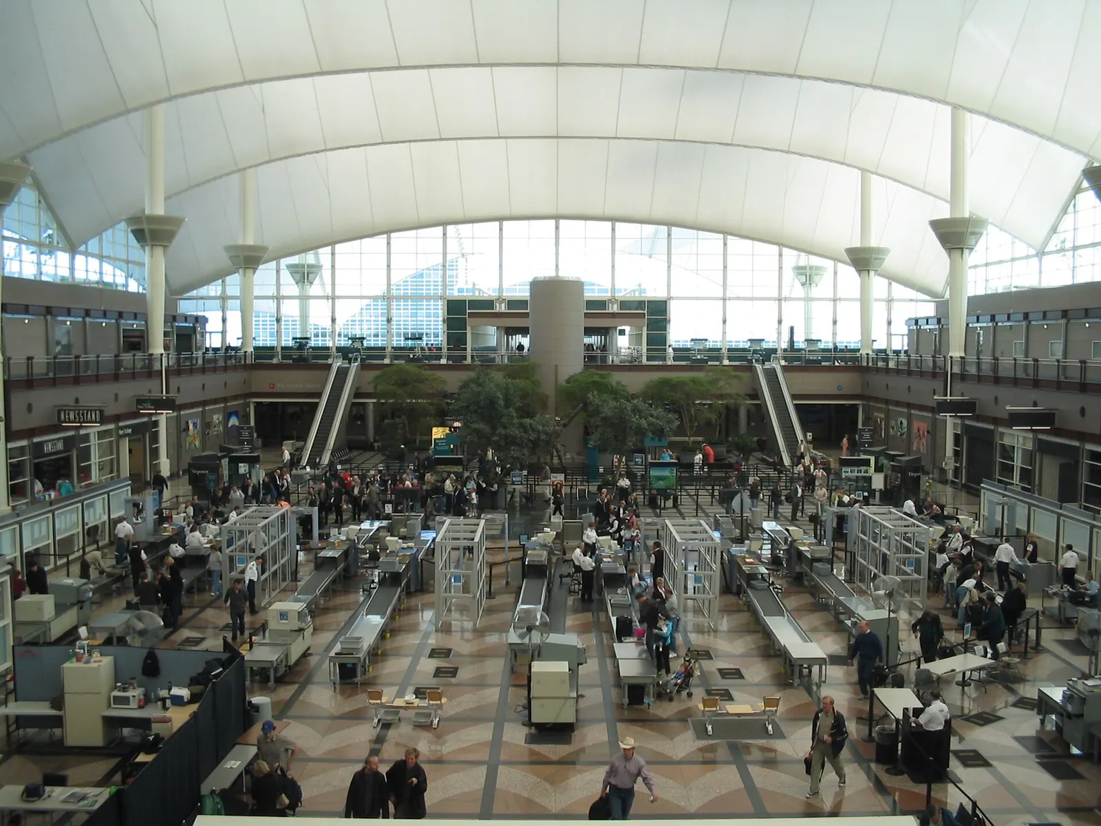 Passengers queue at TSA security screening lanes beneath the vaulted ceiling of Denver International Airport's main terminal.