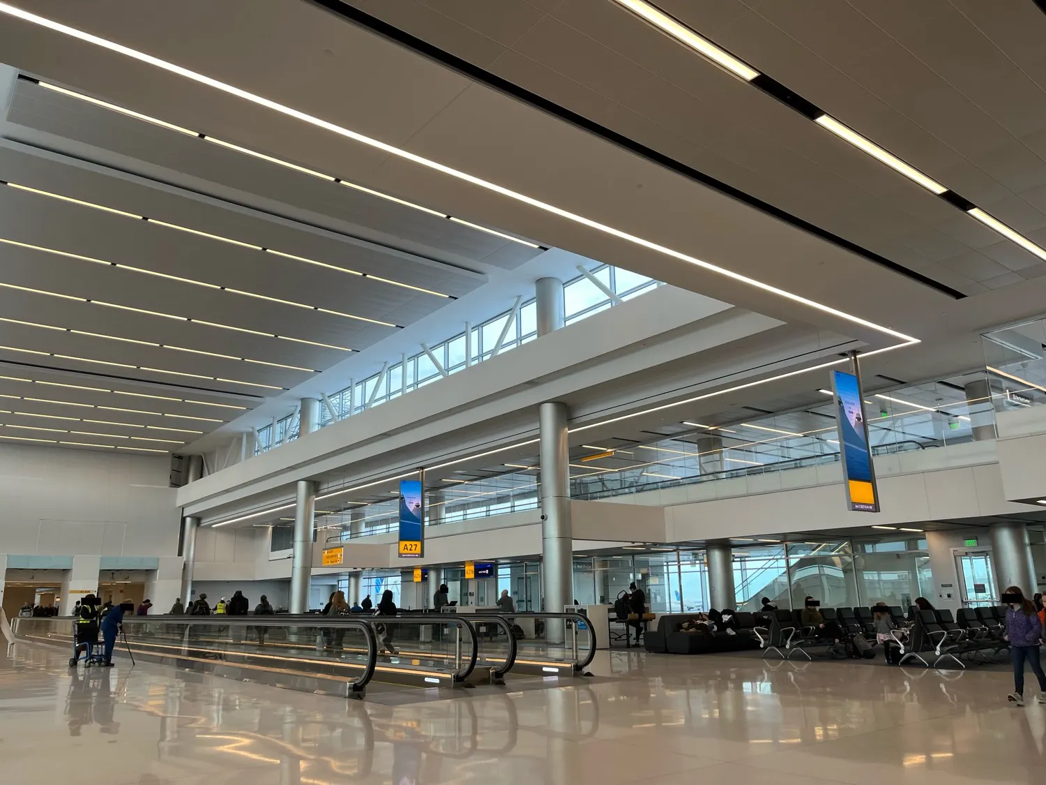 Wide walkways and gate seating areas line the renovated interior of Concourse A at Denver International Airport.
