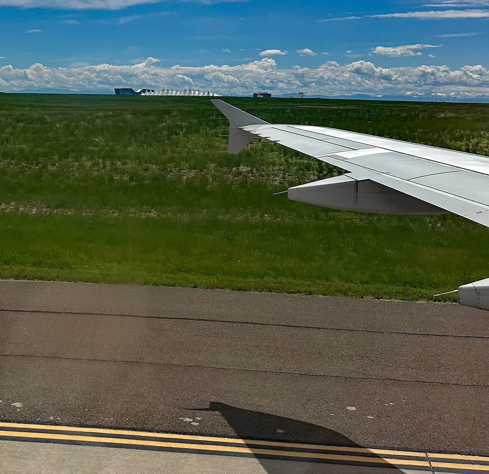 The Jeppesen Terminal, its fabric roofs, and the adjoining Westin hotel are viewed from a distant runway at Denver International Airport.