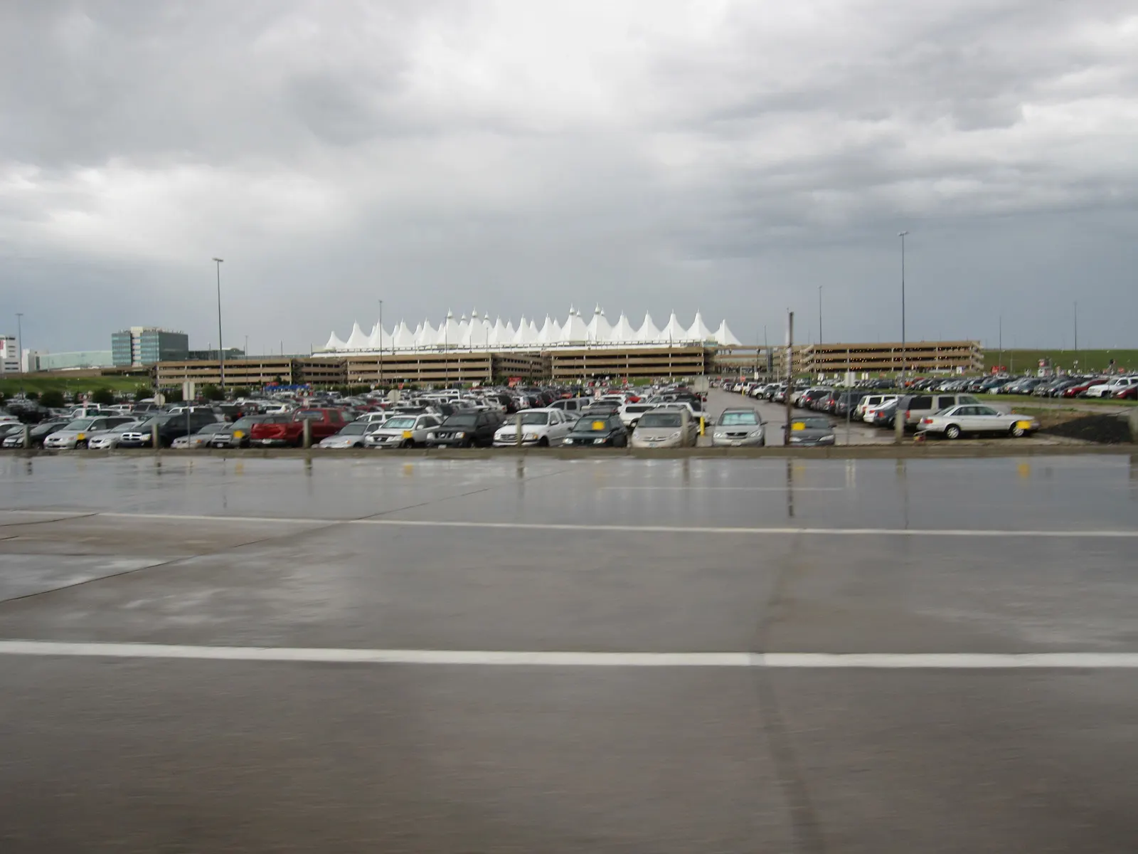 White peaked fabric roof spires rise above the main Jeppesen Terminal at Denver International Airport under a clear sky.