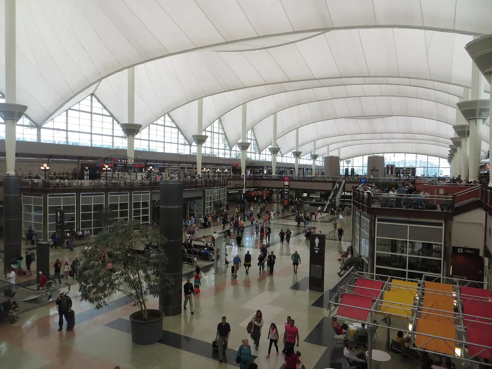 Travelers and baggage carts fill the high-ceilinged north end of the Jeppesen Terminal at Denver International Airport.