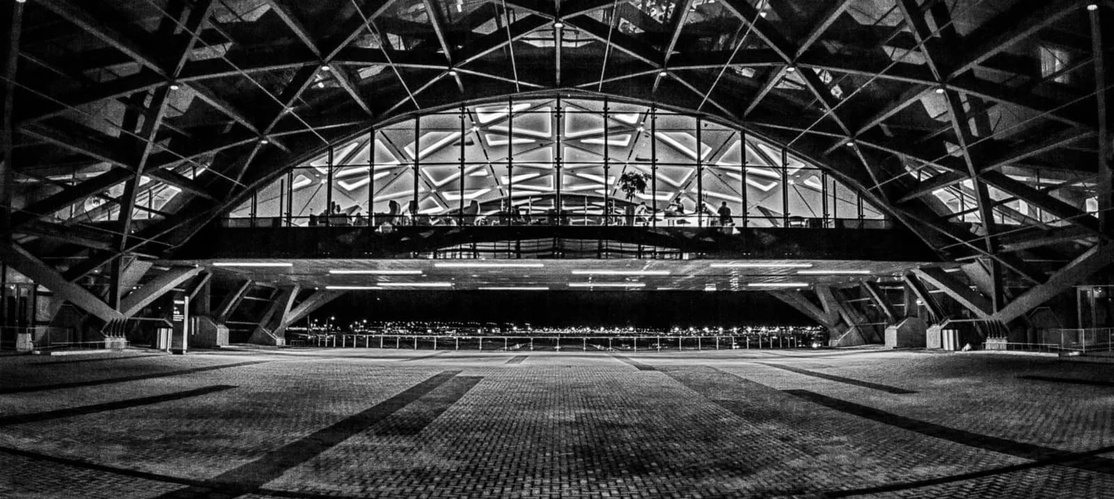 The lit lobby of the Westin hotel and approach roads glow at night from the Denver International Airport transit center deck facing east.